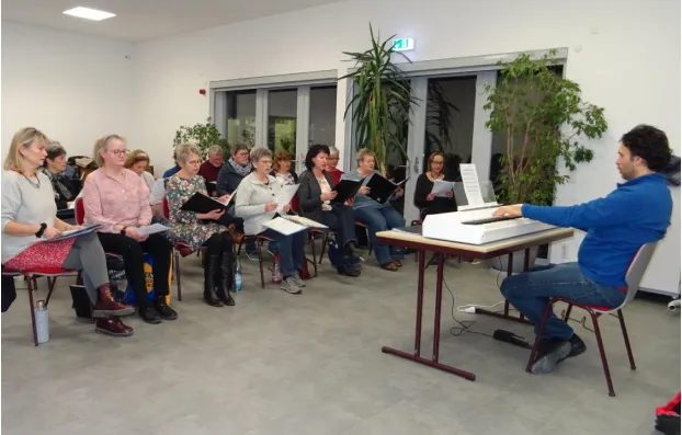 Chorprobe in der Aula der Prohner Schule mit Chormitgliedern und musikalischen Chorleiter Alexandru Constantinescu